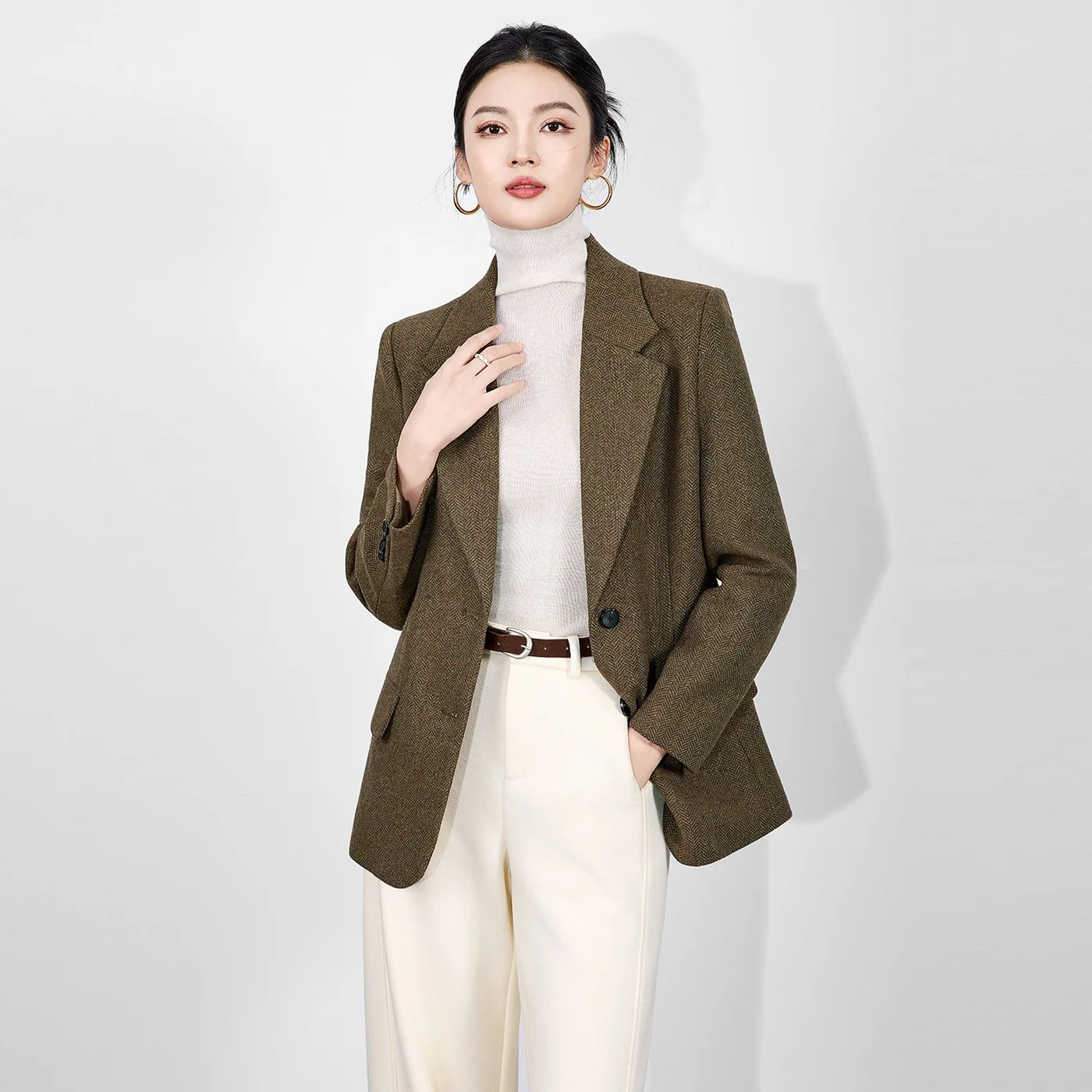 Herringbone Wool-Blend Blazer — An olive-brown herringbone blazer with notch lapels, two buttons and flap pockets, worn by a model against a white ground and shown flat