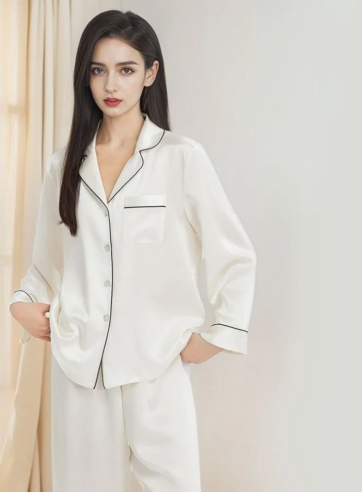 19-Momme Silk Pyjama Set — A woman standing in a long-sleeved silk pyjama set with a notched lapel collar and contrast piping, shown in cream white, navy, wine red and mist purple